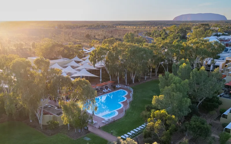 Pool and gum trees at Sails in the Desert with the rock on the horizon, the closest hotel base for Uluru tours, Yulara Northern Territory